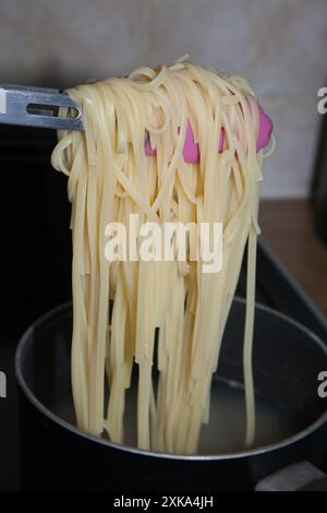 Le tagliatelle vengono cotte in casa e bollite in una padella su un piano cottura Foto Stock