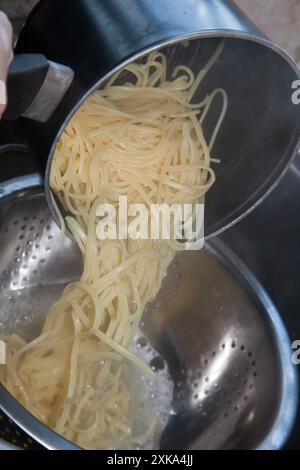 Le tagliatelle vengono cotte in casa e versate dall'ebollizione per essere tese Foto Stock