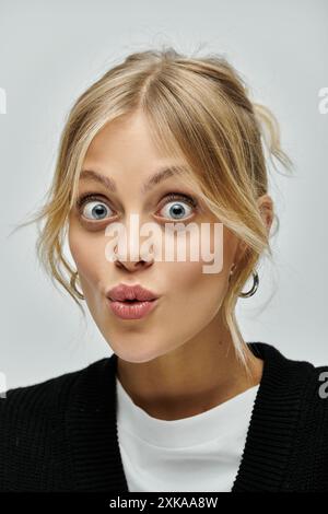 Una giovane donna elegante dai capelli biondi che indossa un abbigliamento casual sembra sorpresa. Foto Stock