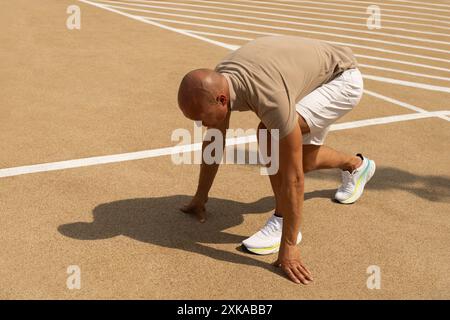 Allenatore sportivo, principianti, runner e atletico in posizione di corsa sul campo sportivo. Pronti per la corsa. Ombra dura e soleggiata. All'aperto. Allenati all'aria aperta sullo sfondo urbano. Allenamento CrossFit. Sfondo banner Foto Stock