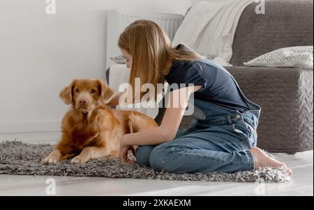 La ragazza di 11 anni gioca con Nova Scotia Retriever Toller a casa sul pavimento Foto Stock