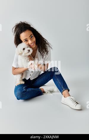 Donna seduta sul pavimento, con un cane bianco. Foto Stock