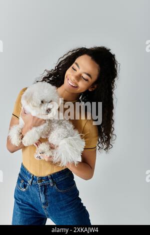 Donna che culla delicatamente la sua soffice frise bichon bianca nelle sue mani. Foto Stock