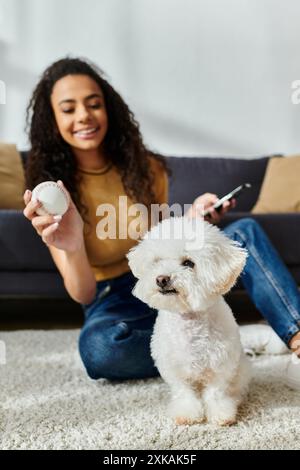 La donna si siede pacificamente con la sua frise bichon bianca sul pavimento. Foto Stock