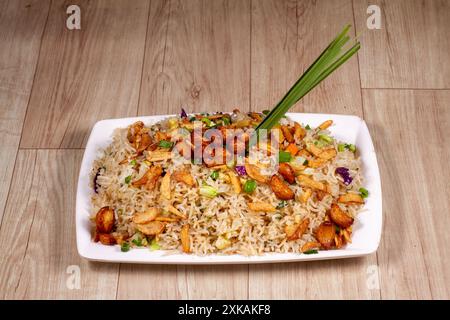 Primo piano di riso fritto con verdure all'aglio bruciato in un piatto di ceramica bianca. Foto Stock