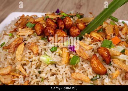 Primo piano di riso fritto con verdure all'aglio bruciato in un piatto di ceramica bianca. Foto Stock