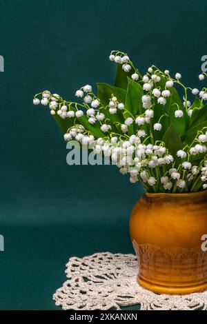 un bouquet di gigli bianchi della valle in un vaso su sfondo verde. Delicata natura morta primo piano Foto Stock