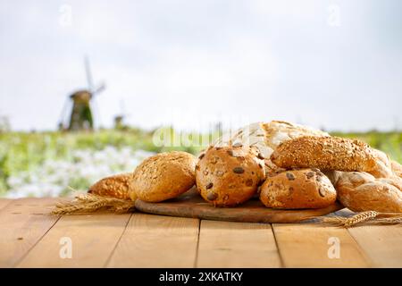 Panini appena sfornati su un tavolo di legno sullo sfondo di un campo di grano. Spazio di copia per i prodotti. Immagine e concept campagna per la visualizzazione del montaggio dei prodotti. Foto Stock