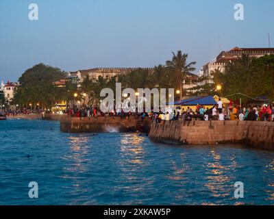 Città di pietra, Zanzibar, Tanzania - Jan 2021: Folla della gente sui giardini di Forodhani e bambini che saltano in acqua da un muro durante la serata ti Foto Stock