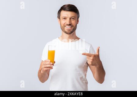 Uomo che tiene un bicchiere di succo d'arancia e punta Foto Stock