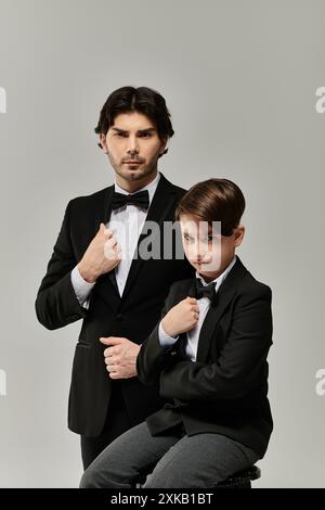 Un padre e un figlio posano in corrispondenza dei smoking, il figlio seduto, il padre in piedi. Foto Stock