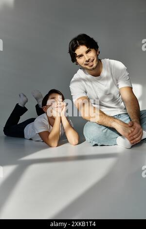 Padre e figlio trascorrono del tempo insieme in uno studio, con il padre seduto e il figlio sdraiato. Foto Stock