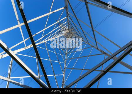 Pilone della rete elettrica ad alta tensione visto dal basso e dal cielo blu Foto Stock