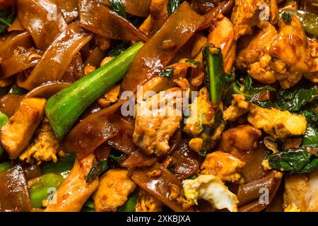 Salato cuscinetto asiatico ammira gli spaghetti alle erbe con pollo e broccoli Foto Stock