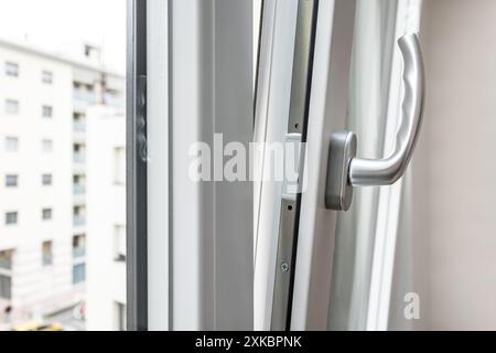 Dettaglio apertura finestrino in alluminio. Finestra inferiore appesa. Vista ravvicinata del telaio della porta in PVC e metallo. Elegante impugnatura cromata. Efficienza energetica e profilo di sicurezza. Urbano Foto Stock