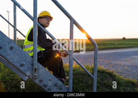 Ingegnere con tablet digitale controlla le turbine eoliche. Foto Stock