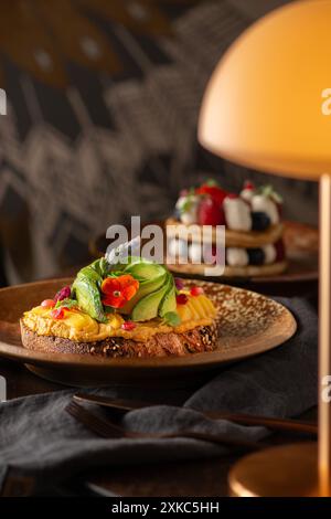 Brindisi all'avocado e all'hummus su un tavolo del ristorante. Ora del brunch. Pane a lievitazione naturale. Foto Stock