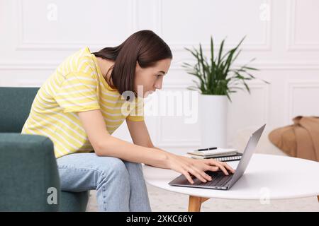 Donna con postura scarsa che usa un notebook a casa Foto Stock