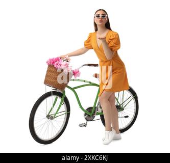 Donna in occhiali da sole con bicicletta e cesto di fiori di peonia che soffiano bacio isolato su bianco Foto Stock