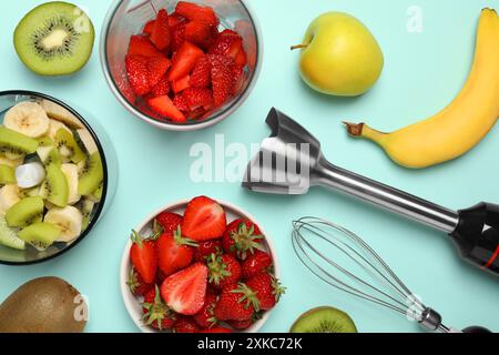 Kit frullatore a immersione, frutta fresca e fragole su sfondo turchese, piatto Foto Stock