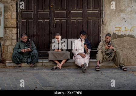 Gli uomini arabi locali seduti sul portico del vecchio edificio saudita nella storica Jeddah (al Balad) nell'area del mercato, in Arabia Saudita. Foto Stock