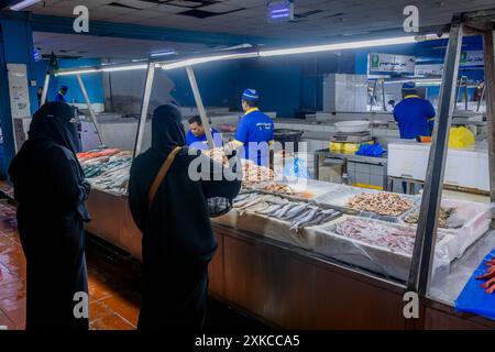 Le donne arabe si sono occupate di paranja al mercato del pesce di Jeddah presso il banco dei frutti di mare in Arabia Saudita. Foto Stock