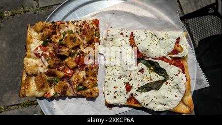 due fette quadrate di pizza siciliana (mozzarella bianca fresca foglie di basilico crosta sottile) su vassoio rotondo con carta pergamena (cibo italiano) pepe rosso Foto Stock