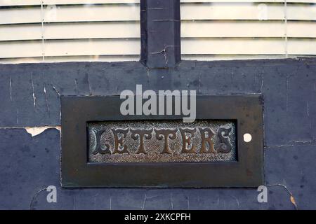 Primo piano di uno slot per lettere ornato nella porta d'ingresso di una vecchia casa Foto Stock