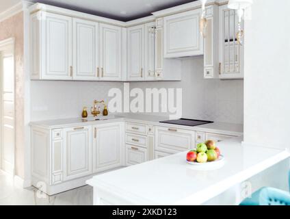 Luminosa ed elegante cucina bianca con accenti dorati, dotata di mobili ed elettrodomestici moderni. Riprese in interni eleganti e ben illuminati. Foto Stock