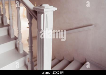 Primo piano di una classica ringhiera bianca per scale con dettagli intricati su sfondo beige. Foto Stock