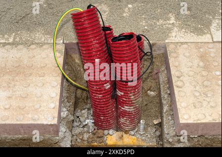 Immagine di condotti ondulati rossi con cavi neri in una struttura in calcestruzzo, che rappresenta il lavoro di installazione elettrica o lo sviluppo di infrastrutture. Foto Stock