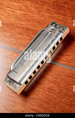L'armonica diatonica a 10 buche d'epoca è appoggiata sul retro di una chitarra acustica rovesciata: Phillip Roberts Foto Stock