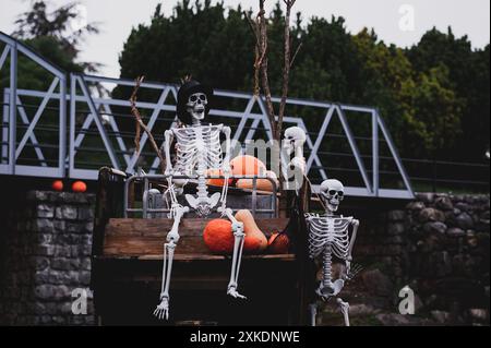Scheletro umano bianco su carrozza di legno con zucche. Decorazione di Halloween. Foto Stock