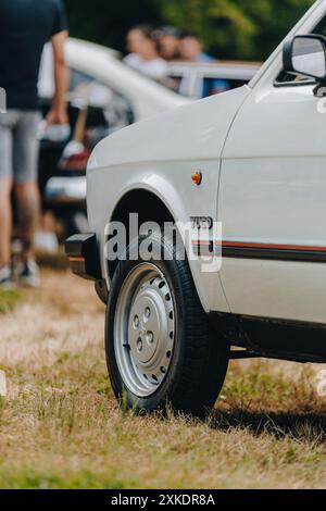 Un'auto Yugo bianca è parcheggiata sull'erba, con pneumatici anteriori e ruote a fuoco. Foto Stock