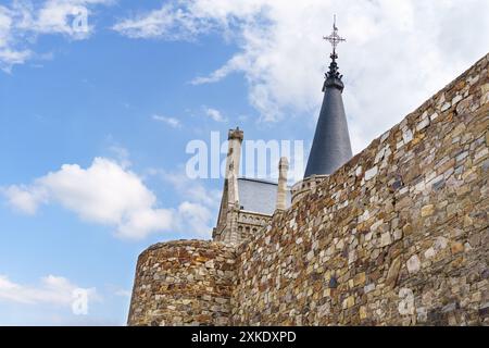 Astorga, Spagna - 3 giugno 2023: Un muro di pietra del Palazzo Episcopale di Astorga, Spagna, con una torre appuntita che si innalza sopra, adagiata contro un cielo blu con Foto Stock