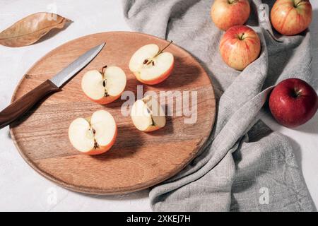 Mele fresche mature su vassoio di legno con tovagliolo grigio su tavolo bianco. Vendemmia autunnale, concetto del Ringraziamento. Vista dall'alto. Foto Stock