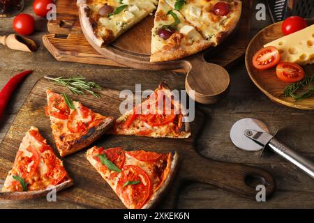 Tavole con gustose pizze, ingredienti e taglierina su fondo in legno Foto Stock