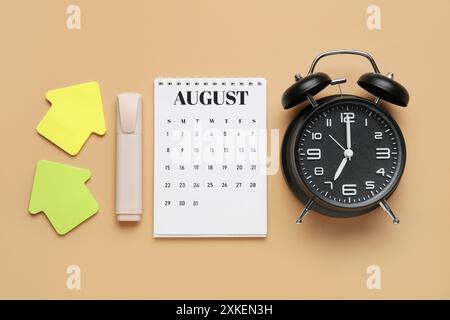 Calendario con sveglia e cancelleria su sfondo beige Foto Stock