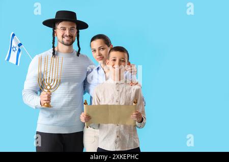 Felice famiglia ebraica con libro di Esther e bandiera israeliana su sfondo blu Foto Stock