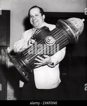 New York, New York 11 marzo 1955 Joseph Baroncini gestisce un sorriso in una stazione di polizia qui oggi mentre è passato a guardare un idrante realistico, ma fittizio, che è stato la causa della sua auto etichettata per una violazione del parcheggio mercoledì sera. Un poliziotto ha preso il biglietto per l'auto, ma al ritorno ha trovato la spina e l'auto era scomparsa. La sera successiva, il poliziotto ha trovato di nuovo la spina e, dopo un'ispezione, l'ha trovata una falsa, apparentemente una TV o un palcoscenico. Baroncini ha detto che la sua auto era parcheggiata da un portiere, e intanto è in attesa di rispondere a una citazione al tribunale del traffico 17 marzo. Foto Stock