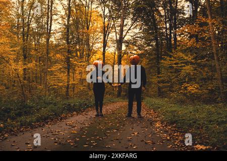 donna incinta che si diverte con l'uomo in costume di halloween. testa di zucca Foto Stock