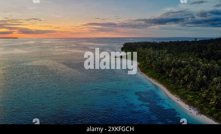 Una vista aerea della costa di Sumatra durante il tramonto, che mostra lo stupefacente contrasto tra lussureggianti foreste tropicali e vibranti acque turchesi. Foto Stock