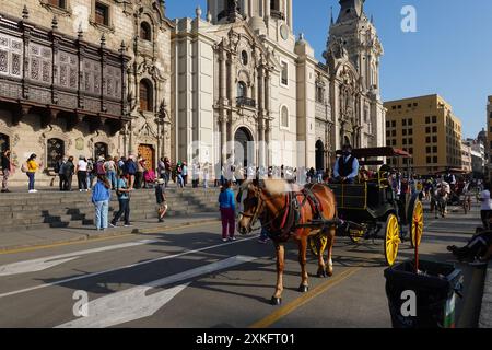 Lima, Perù - 16 aprile 2022: Una carrozza a cavallo passa il tempo coloniale il Palazzo dell'Arcivescovo e la Cattedrale di Lima in Plaza Mayor, capitale del Perù Foto Stock