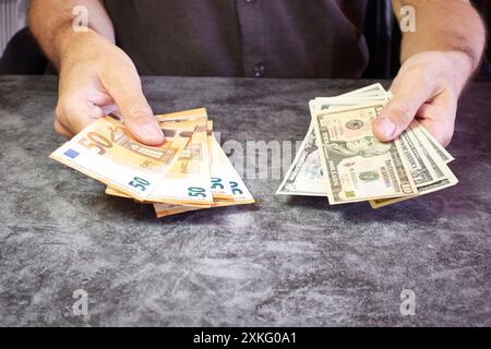 Uomo che mostra una fetta di banconote da un dollaro in una mano e euro nell'altra Foto Stock