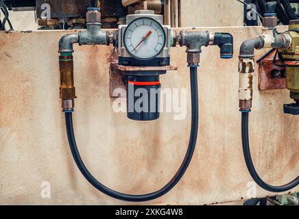 Manometro per la misurazione della pressione contro la vecchia parete verniciata con tubi in gomma. Concetto industriale Foto Stock