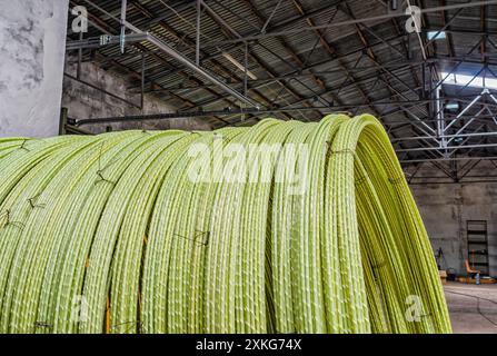 Fili di plastica gialli attorcigliati in rotoli in officina. Produzione di fili per raccordi. Costruzione Foto Stock