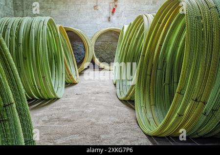 Fili di plastica gialli attorcigliati in rotoli in officina. Produzione di fili per raccordi. Costruzione Foto Stock