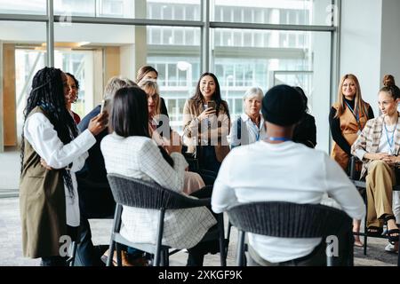 Un gruppo eterogeneo di professionisti impegnati in una vivace discussione durante un seminario, ambientato in un moderno ambiente di ufficio. Foto Stock