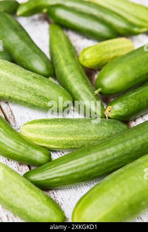 Una collezione di cetrioli verdi freschi su fondo rustico in legno, che rappresenta una raccolta estiva sana e biologica dal giardino. Foto Stock