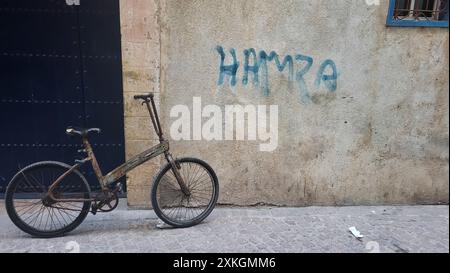 Una vecchia bici si appoggia contro il muro della Medina a Essaouira in Marocco. Foto Stock